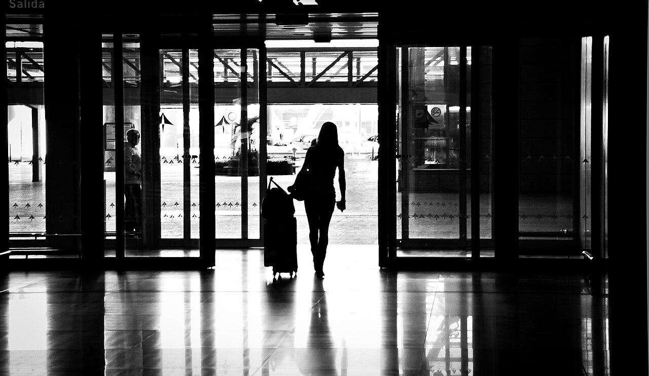 A woman leaving an airport with her suitcase